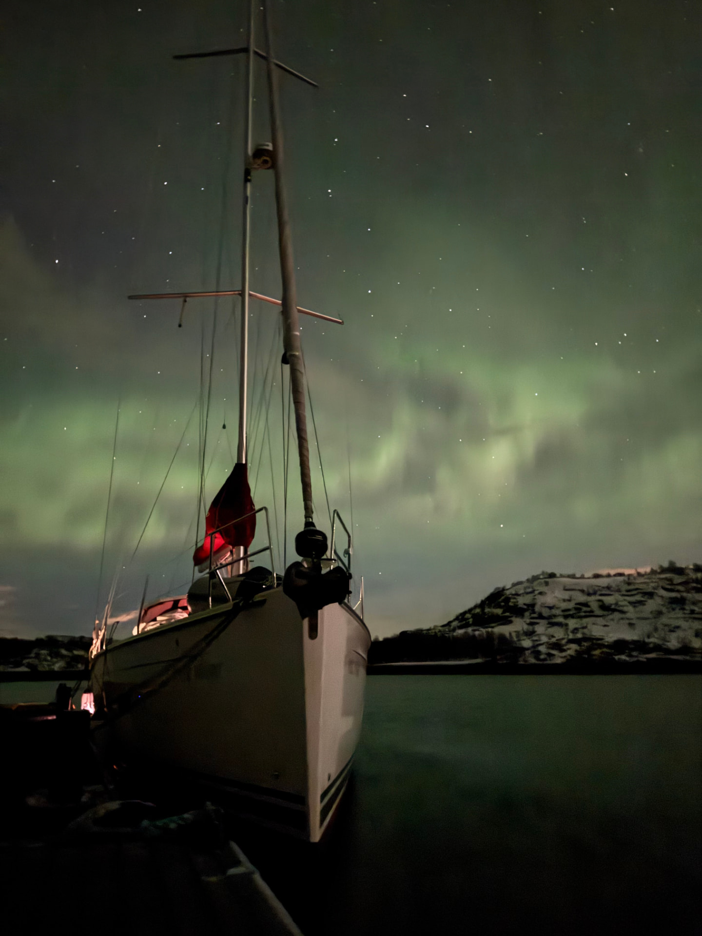 Boreal yacht anchored beneath the northern lights in a dark fjord near Tromsø