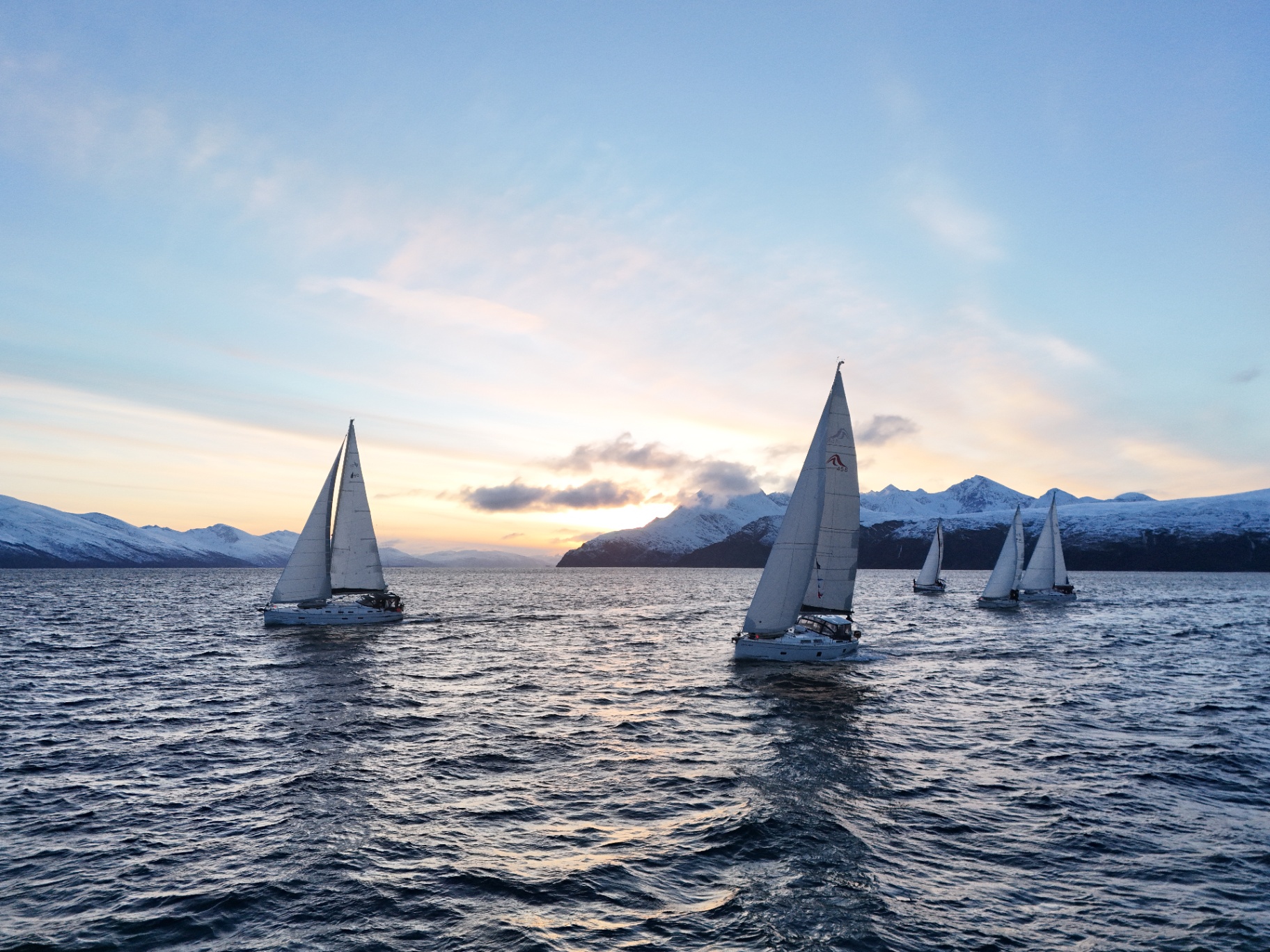 Sailing yacht in Arctic Norway with snow-capped mountains